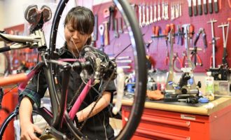 写真：女性用自転車を組み立てる女性スタッフ
